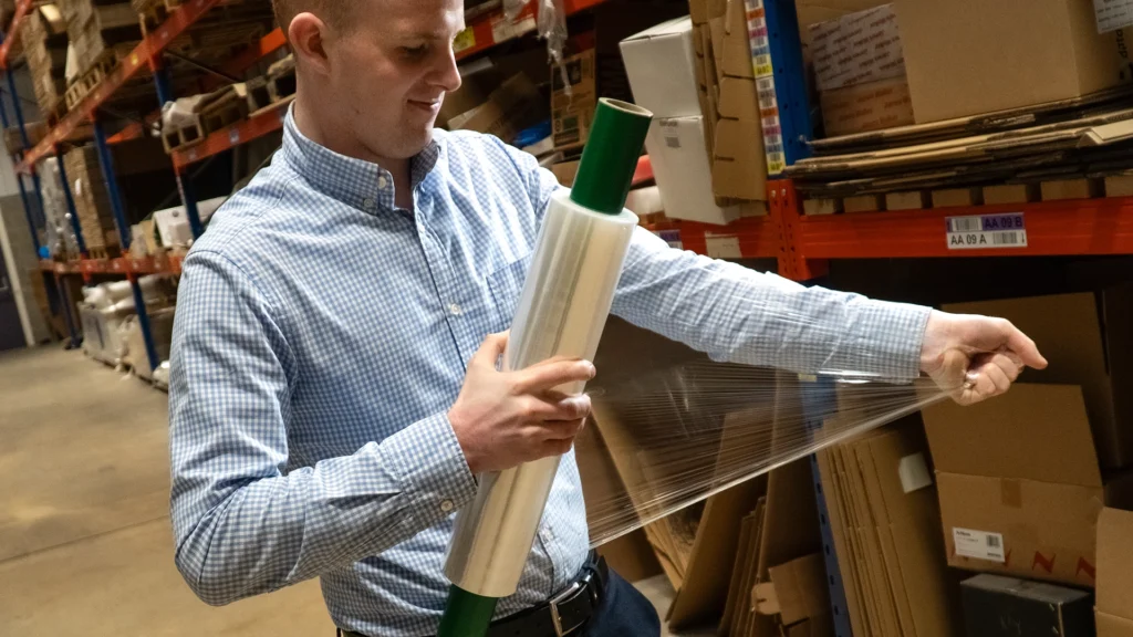 Man pulls hand pallet wrap tight to test it's strength.