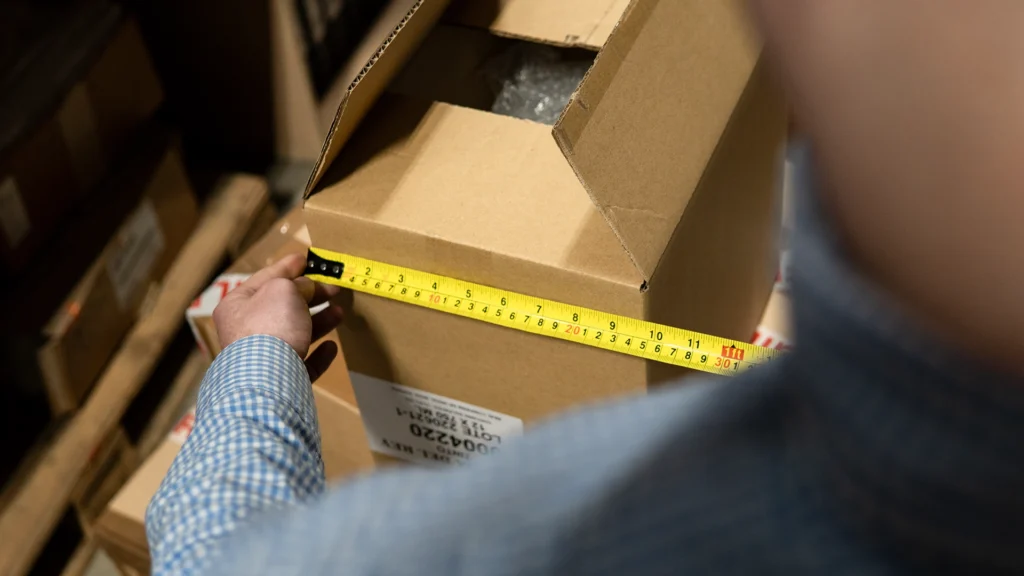 Employee measures box ready for shipping.