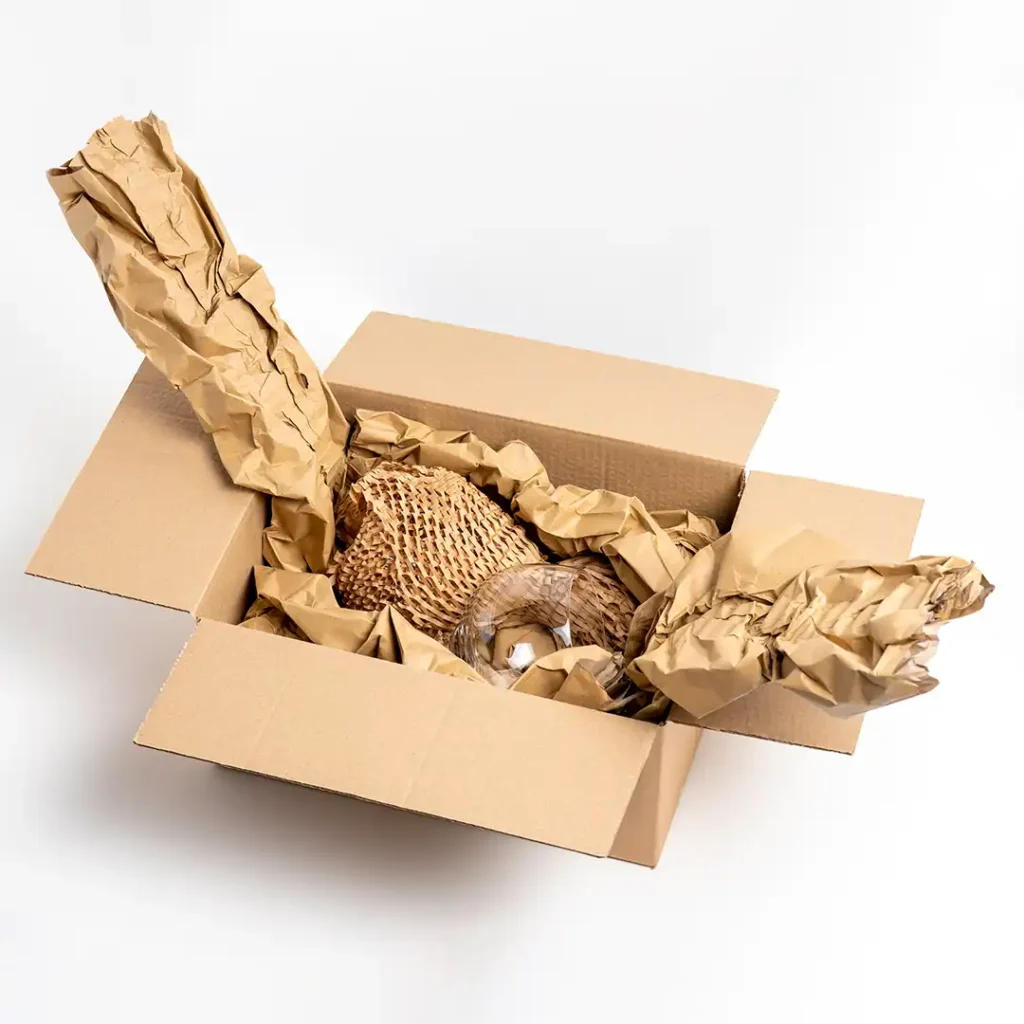 Cardboard box with a glass cup inside, which is wrapped in Hexcel and placed on top of void fill