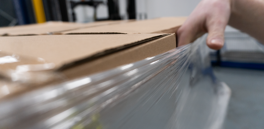 Hand testing the film tension of boxes wrapped in pallet wrap