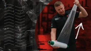 Technical Manager pulling pallet wrap to maximum stretch, with red and white graphics