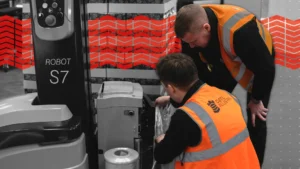 Two pallet wrap consultants reviewing pallet wrapper set up in a warehouse