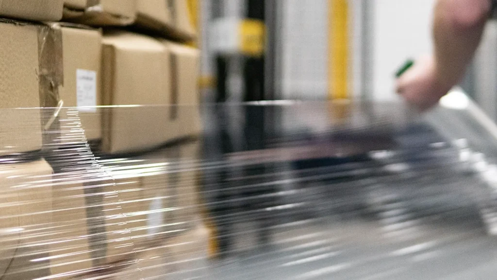Pallet wrap being stretched around a stack of cardboard boxes