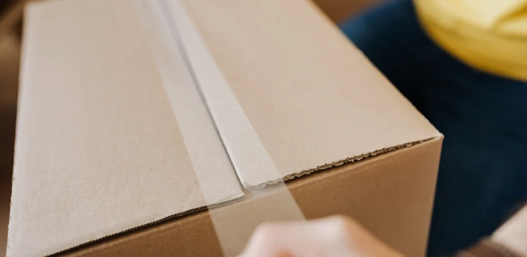 close up of adhesive tape being applied to close a cardboard box lid